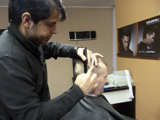 The barber is cutting his customers hair